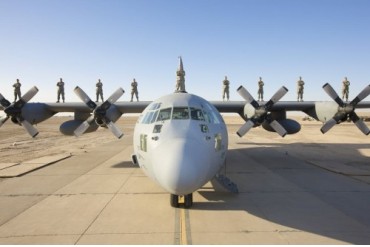 Troops stand on the wings of a C-130 Hercules at parade rest.